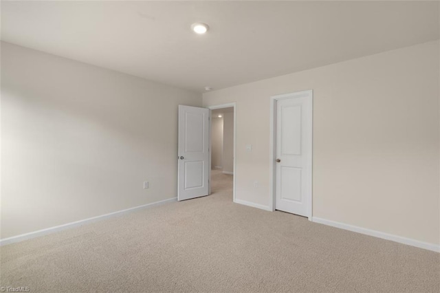 unfurnished room featuring light carpet and baseboards