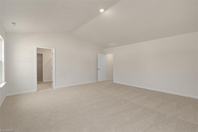 interior space with lofted ceiling, visible vents, light colored carpet, a spacious closet, and baseboards