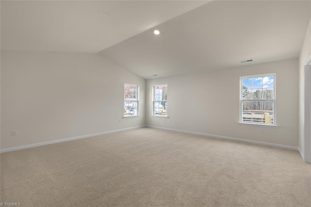 unfurnished room featuring lofted ceiling, a healthy amount of sunlight, baseboards, and light colored carpet