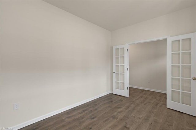 spare room with dark wood-style floors, french doors, and baseboards