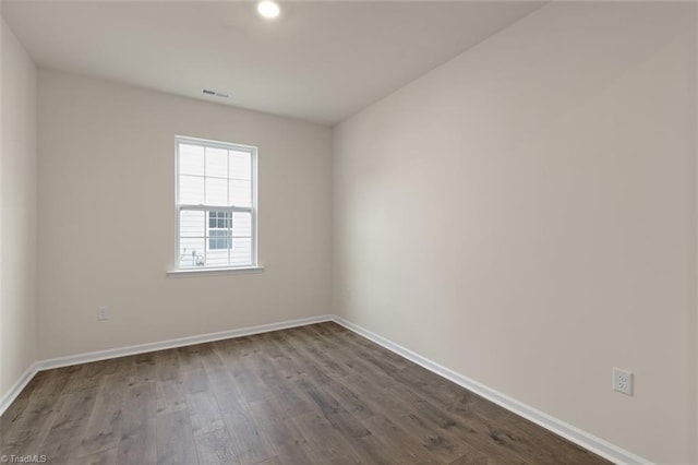 spare room featuring dark wood-style floors, baseboards, and visible vents