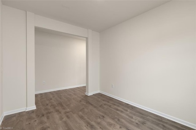 unfurnished bedroom with dark wood-style floors, a closet, and baseboards