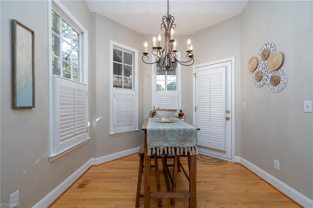 dining space with plenty of natural light, a chandelier, and light wood-type flooring