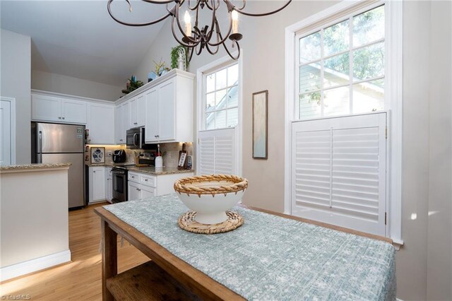 kitchen featuring pendant lighting, light hardwood / wood-style floors, white cabinets, and appliances with stainless steel finishes