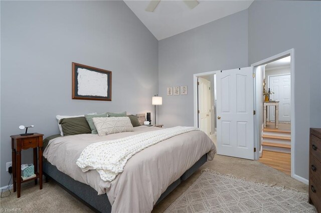 carpeted bedroom with ceiling fan and high vaulted ceiling