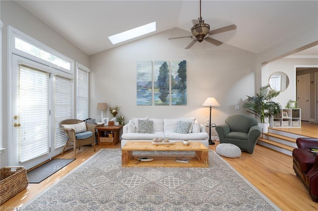 living room with ceiling fan, hardwood / wood-style floors, and lofted ceiling with skylight