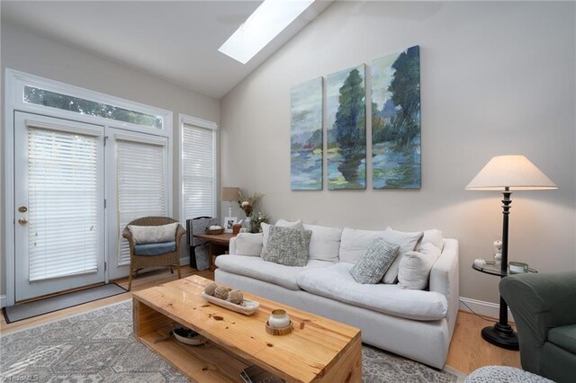 living room with vaulted ceiling with skylight and wood-type flooring