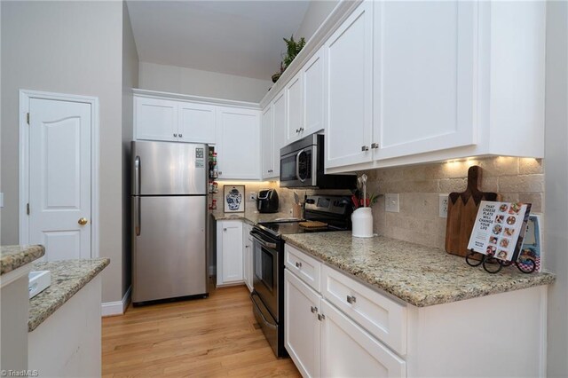 kitchen featuring light wood-type flooring, light stone counters, decorative backsplash, stainless steel appliances, and white cabinetry