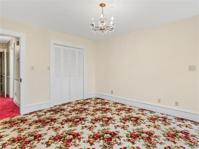 unfurnished bedroom with a closet, an inviting chandelier, and carpet floors