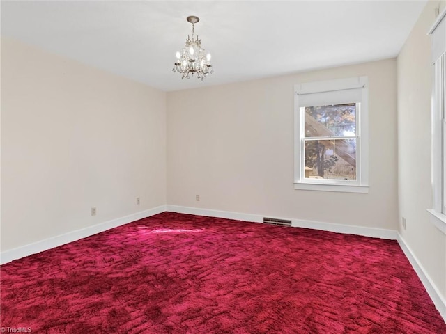 carpeted spare room featuring a notable chandelier