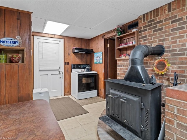 kitchen featuring wood walls, a wood stove, a paneled ceiling, white range with electric stovetop, and light tile patterned floors