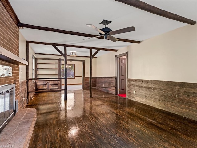 unfurnished living room with beamed ceiling, a wealth of natural light, and a brick fireplace