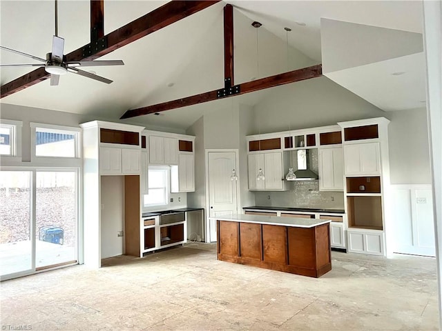 kitchen featuring wall chimney range hood, pendant lighting, a kitchen island, high vaulted ceiling, and ceiling fan