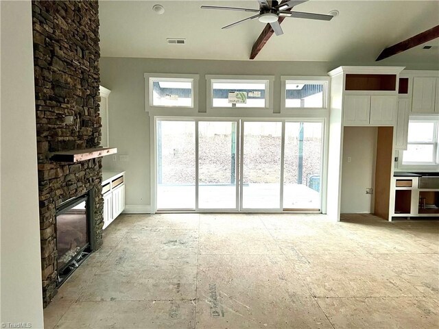 unfurnished living room featuring a stone fireplace and ceiling fan