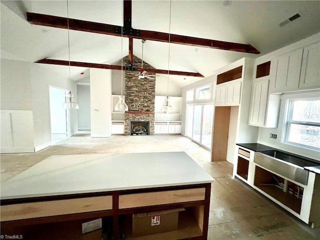 kitchen with beam ceiling, decorative light fixtures, a fireplace, and high vaulted ceiling