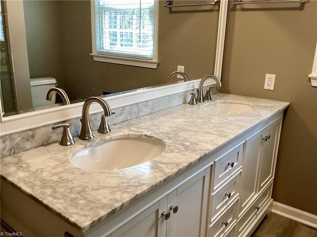 full bathroom featuring a sink, baseboards, toilet, and double vanity