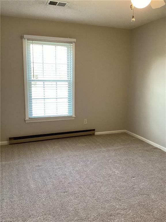 empty room with a baseboard heating unit, baseboards, and carpet