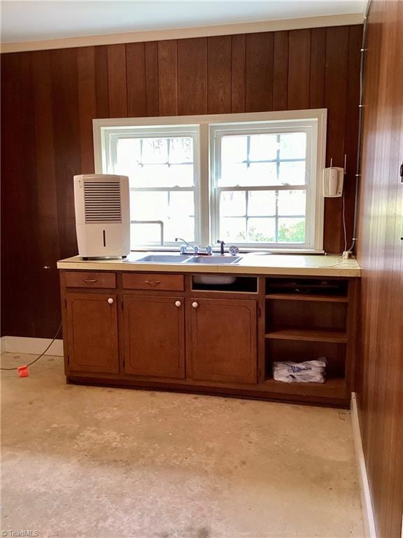 interior space featuring brown cabinets, a sink, open shelves, wood walls, and light countertops