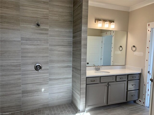 bathroom featuring tiled shower, ornamental molding, and vanity