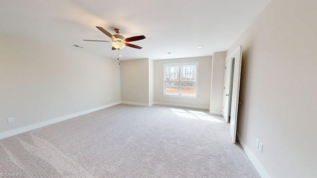 empty room featuring light carpet, visible vents, baseboards, and ceiling fan