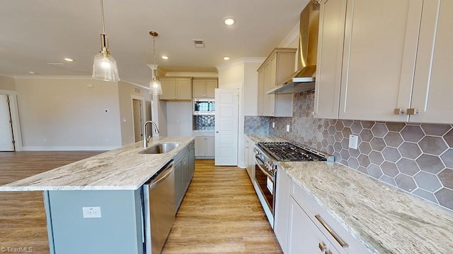 kitchen featuring visible vents, light wood-style flooring, a sink, stainless steel appliances, and wall chimney range hood