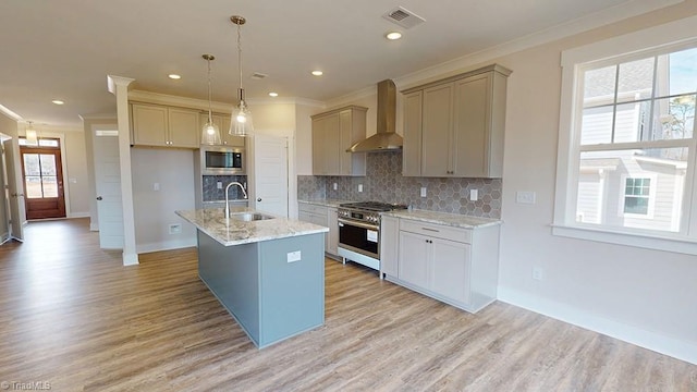 kitchen featuring a sink, backsplash, stainless steel appliances, crown molding, and wall chimney range hood