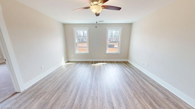 unfurnished room featuring wood finished floors, a ceiling fan, visible vents, and baseboards