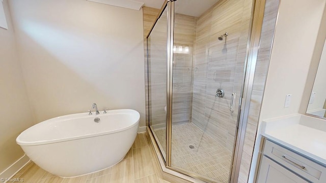 full bathroom with a shower stall, a freestanding bath, vanity, and baseboards