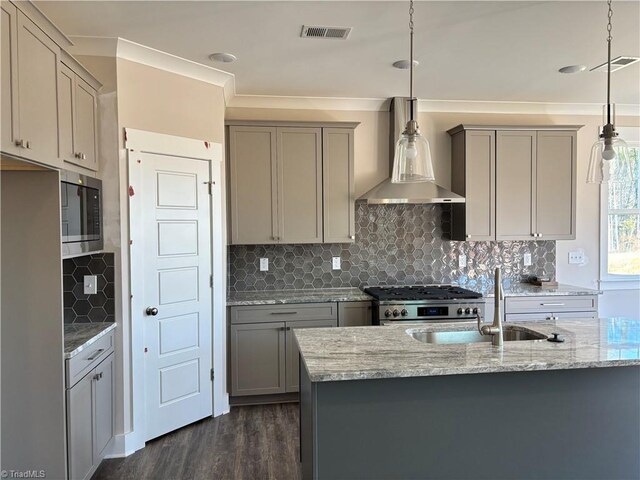 kitchen with visible vents, gray cabinets, appliances with stainless steel finishes, wall chimney exhaust hood, and a sink