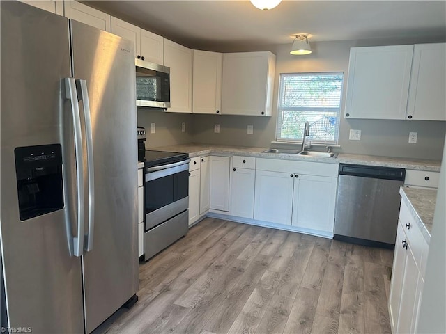 kitchen featuring white cabinetry, sink, stainless steel appliances, and light wood-type flooring