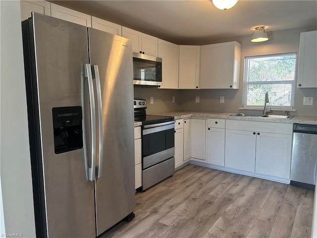 kitchen with light stone countertops, stainless steel appliances, sink, light hardwood / wood-style floors, and white cabinetry