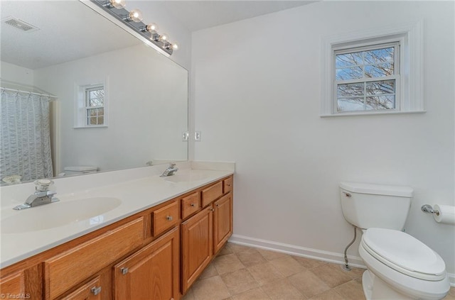 bathroom featuring visible vents, double vanity, a sink, and toilet