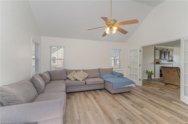 living area with high vaulted ceiling, plenty of natural light, light wood-style flooring, and a ceiling fan