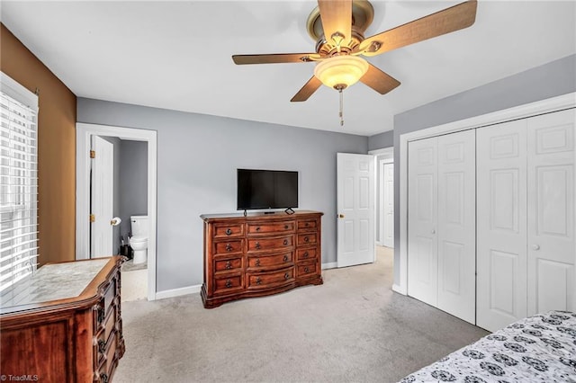 bedroom with ensuite bathroom, light colored carpet, ceiling fan, and a closet