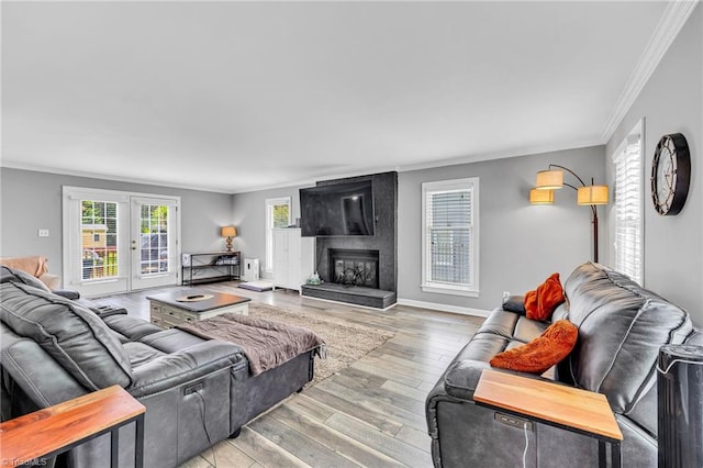 living room featuring ornamental molding, light wood-type flooring, a fireplace, and french doors