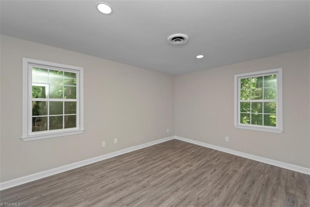 spare room with wood finished floors, baseboards, and recessed lighting