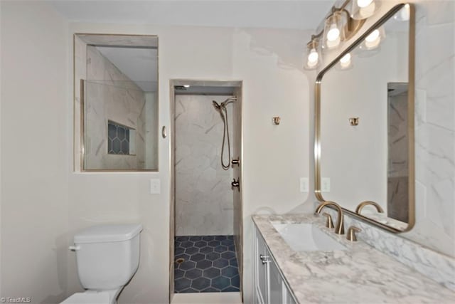 full bath with vanity, a marble finish shower, and toilet