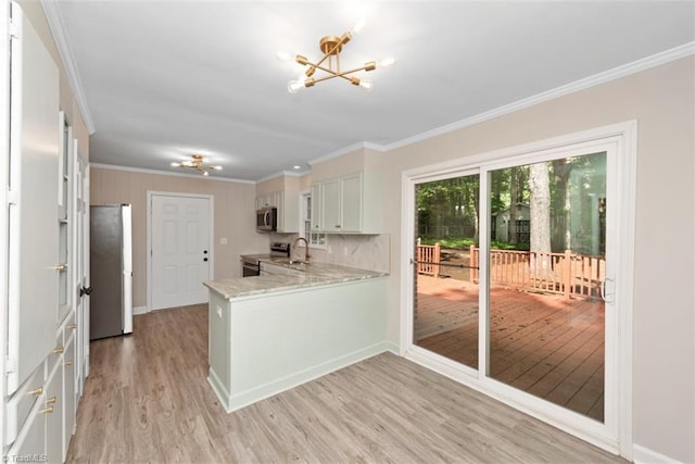 kitchen with appliances with stainless steel finishes, a chandelier, ornamental molding, a sink, and light wood-style floors