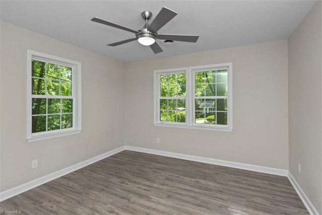 empty room featuring healthy amount of natural light, wood finished floors, and baseboards