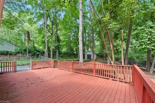 deck featuring a fenced backyard, a storage shed, an outdoor structure, and view of scattered trees