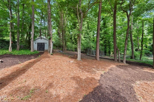 view of yard with fence, an outbuilding, and a shed