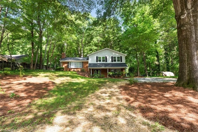 back of property featuring a chimney, brick siding, and covered porch