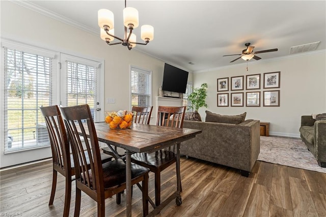 dining area with crown molding, ceiling fan with notable chandelier, and dark hardwood / wood-style floors