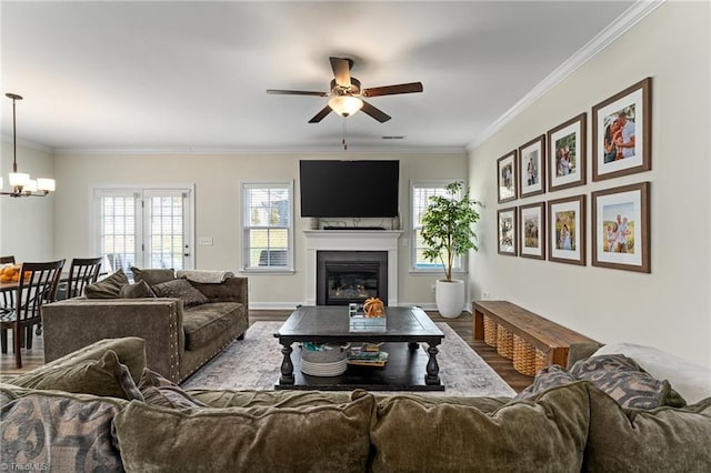 living room featuring ornamental molding, ceiling fan with notable chandelier, and light wood-type flooring