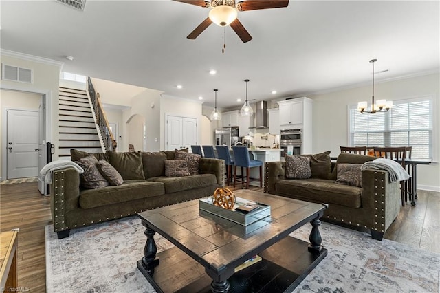 living room with ornamental molding, ceiling fan with notable chandelier, and dark hardwood / wood-style flooring