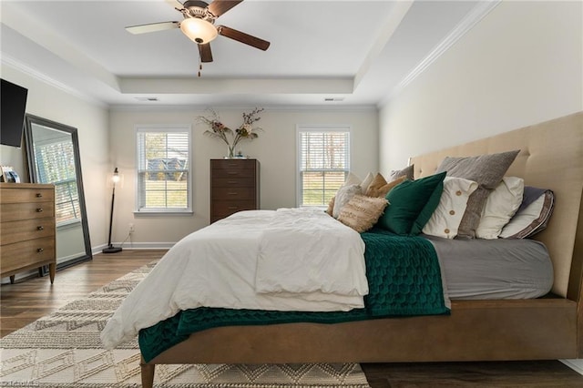 bedroom with multiple windows, hardwood / wood-style floors, and a raised ceiling