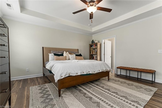 bedroom with dark wood-type flooring, ceiling fan, a tray ceiling, and crown molding