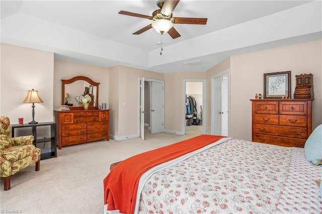 bedroom featuring light carpet, baseboards, a raised ceiling, a ceiling fan, and a closet