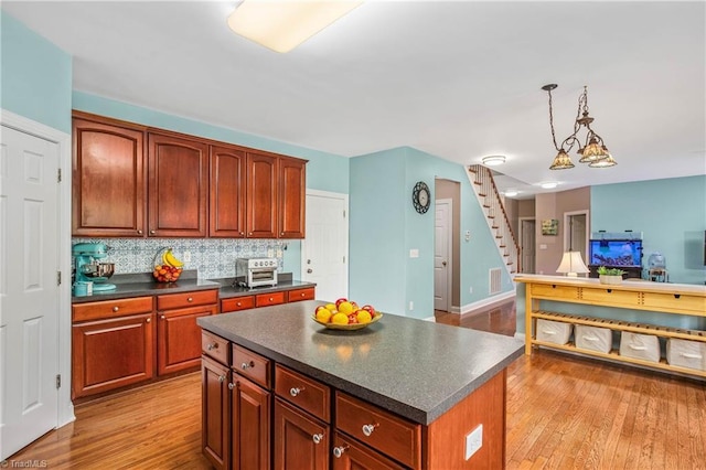 kitchen with hanging light fixtures, dark countertops, light wood-style flooring, and a center island