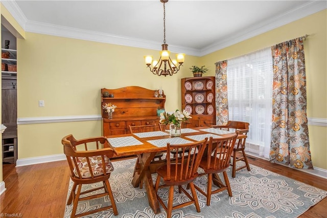 dining space with baseboards, ornamental molding, and wood finished floors